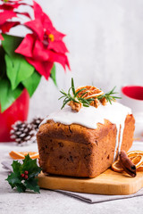 Fruit loaf cake dusted with icing, nuts and dry orange on stone background. Christmas and Winter Holidays Poinsettia on background