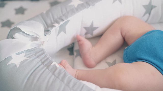 motion past star decorated cocoon with adorable newborn son in bodysuit sucking dump in cot at home