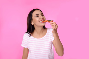 Beautiful woman eating pizza on pink background