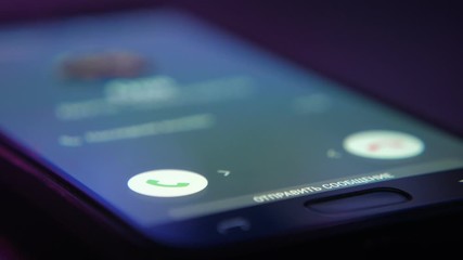 Smartpone lying on a table and suddenly a call rings. Male finger touches screen