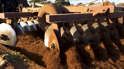Close-up cropped rear view of the plough discs on the back of a tractor ploughing fields on a large scale farm