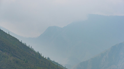 silhouettes of mountains in blue haze. Outline of gentle hills in the valley