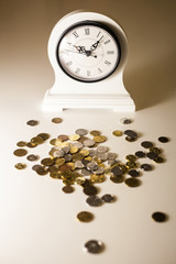 White desk clock on a white background near scattered coins or 