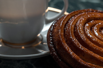 Bun with raisins, cinnamon bun, meat pie on saucer on green marble background