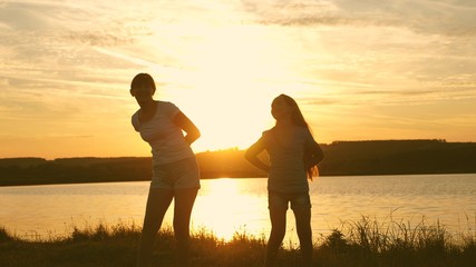 happy girls dancing on the beach. party by lake, children dancing. beautiful girls having fun listening to music. sisters are dancing. teens girlfriends holiday disco.