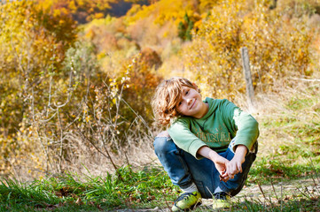 Portrait of a happy fashionable boy in a field against the backdrop of an autumn landscape. Relax in the autumn forest in the mountains outdoors. Child and autumn nature