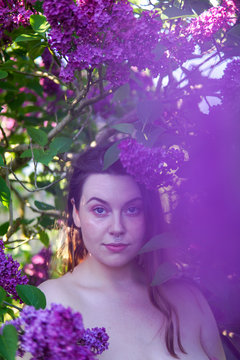 Portrait of a beautiful woman standing amongst purple lilac flowers, England, UK