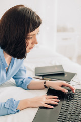 Businesswoman working on her laptop in the white bed. Work at home. Freelancer