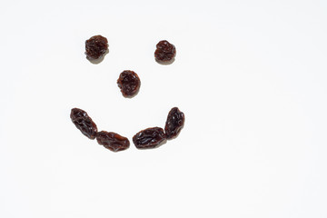 Raisins placed like a smiley isolated on white background. Dried dark grapes. Copy space. Happy food, new year resolution. Diet in the new year concept.