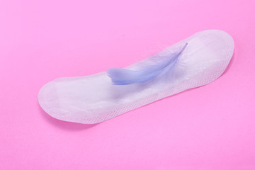 Menstrual pad with feather on color background