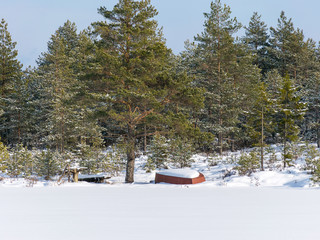 winter landscape with a snow-covered boat on the shore of a lake