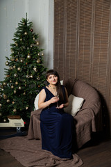 Obraz premium Beautiful young woman with a glass of champagne on a New Year's armchair.