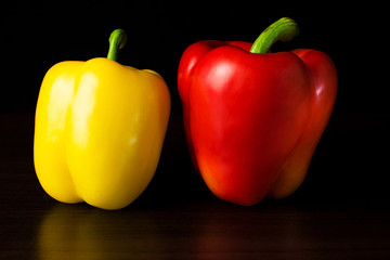 Two red and yellow paprika are lying on the table.
