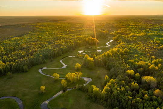 Forest in summer colors. Green deciduous trees and winding blue river in sunset. Mulgi meadow, Estonia, Europe