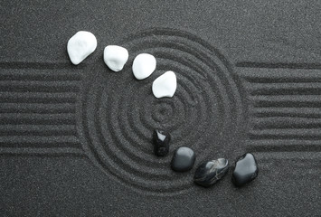 Stones on black sand with beautiful pattern, flat lay. Zen and harmony