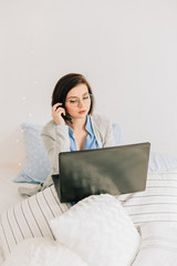 Businesswoman working on her laptop in the white bed. Work at home. Freelancer lifestyle