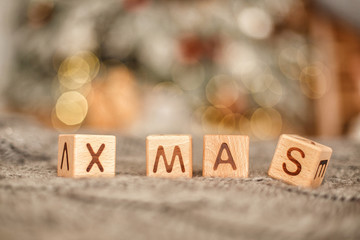 The letters "x mas" on wooden cubes. Christmas bokeh in the background. New year card. Copy space