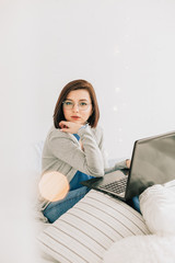 Businesswoman working on her laptop in the white bed. Work at home. Freelancer lifestyle