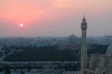 Fototapeta na wymiar The Sun Setting over Manama City with the Minaret of Al Fateh Grand Mosque in Foreground
