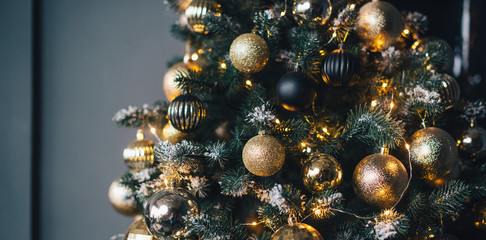 Christmas tree decorated with garlands and golden balls on a dark background