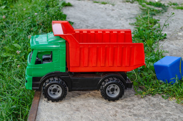 Obraz premium one big colored toy dump truck stands on a stump in the green grass