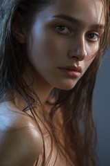 Close up portrait of an attractive model without makeup on a dark background with morning fresh look and wet hair