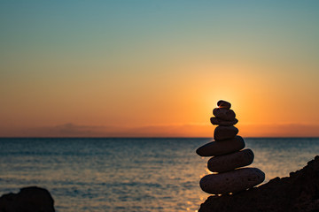 The object of the stones on the beach at sunset. Zen concept. Sunset. Silhouette of stones against the sunset sky