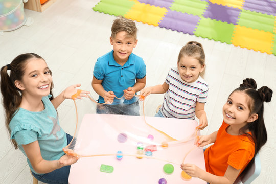 Happy children playing with slime at table indoors, above view