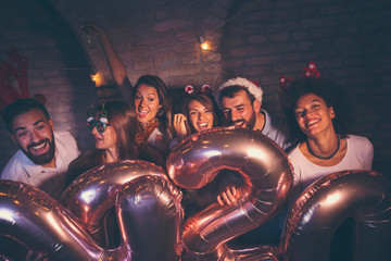 Friends dancing, drinking champagne and holding 2020 balloons at New Years party