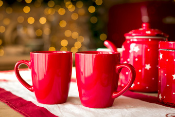 Two red cups on a background of New Year's wooden kitchen in classic brown tones, Christmas morning, New Year's drink in a cozy house