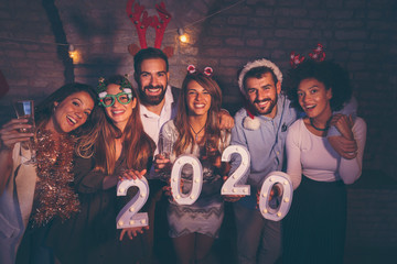 Friends holding illuminative numbers 2020 at New Years party