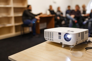 LCD video projector at business conference or lecture in a conference room or office with blurred people background - obrazy, fototapety, plakaty