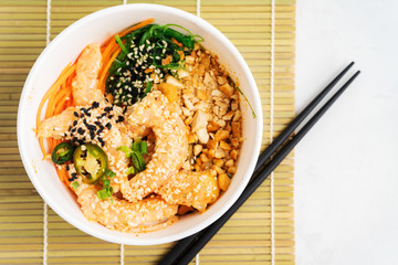 Asian food background with Spicy Shrimp Poke Bowl with rice, seaweeds and sesame seeds, avocado with chopsticks on white. Buddha bowl. Healthy seafood lunch. Diet food. Top view with copy space.