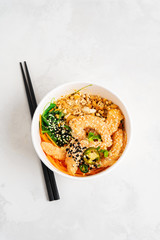 Asian food background with Spicy Shrimp Poke Bowl with rice, seaweeds and sesame seeds, avocado in a lunch box with chopsticks on white. Healthy seafood lunch. Diet food. Top view with copy space.