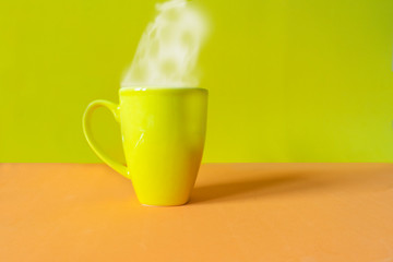 hot cup of yellow coffee on an orange background