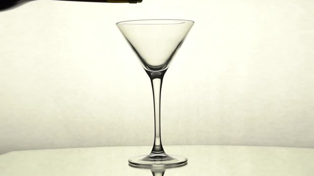 Red wine is poured from a bottle into a Martini glass