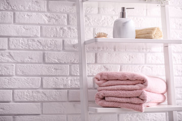 Fototapeta na wymiar Clean towels on shelving unit in bathroom. Space for text