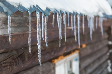 Icicles hang from the roof of a wooden house.