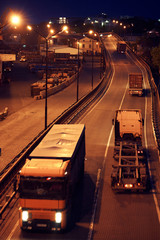 truck with container rides on the road, freight cars in industrial seaport at night