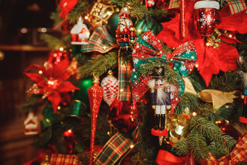 Toy soldier wooden nutcracker statue hanging on decorated Christmas tree, vintage style.Traditional...