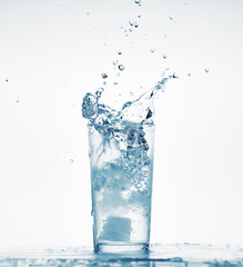 one glass of water with splash from falling ice cube, white background, isolated object