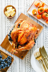 Roasted whole turkey on a festive table with persimmon, blue grape and lemon for family...