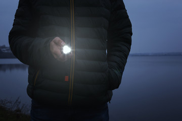 Man with flashlight walking outdoors, closeup view - obrazy, fototapety, plakaty