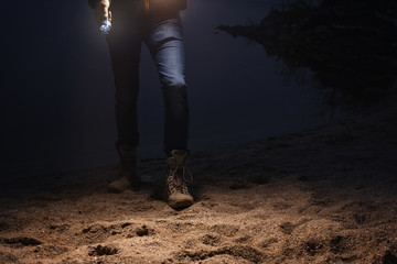 Man with flashlight walking at riverside, closeup