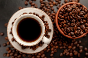 Cup of coffee and different beans on a stone background.