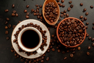 Cup of coffee and different beans on a stone background.