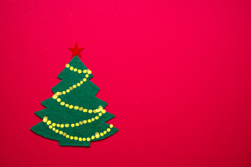 Handmade felt New Year Tree on red paper background.  New Year or Christmas background.