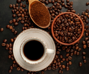 Cup of coffee and different beans on a stone background.