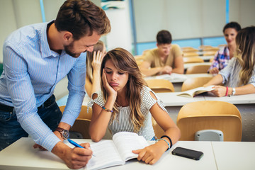 Male tutor teaching university students in classroom.