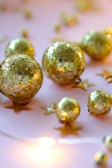 Holographic sparkles in the form of stars and gold balls on a pink background close-up. Template  banner for greeting card your text design 2020. New year, christmas, birthday